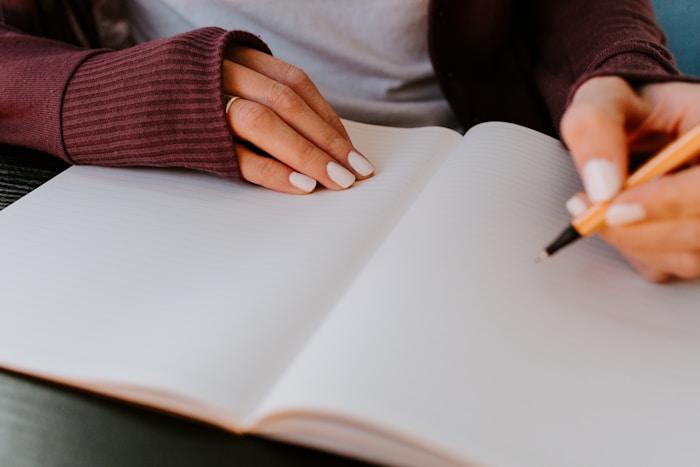 A person writing thoughtfully in an open notebook.